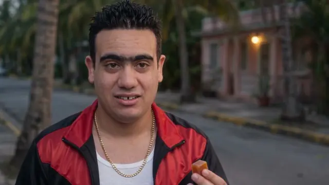 Pachi in a red tracksuit jacket on a street at dusk