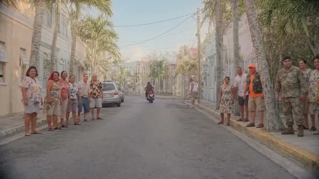 The whole town lined up along a pastel street with palm trees