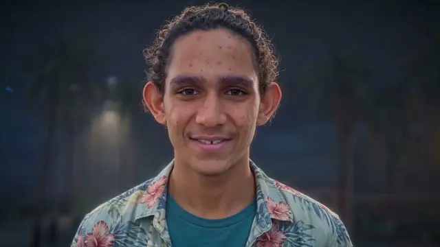Yeyo smiling at night in a flowered shirt