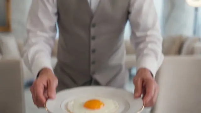 A butler serving a single fried egg