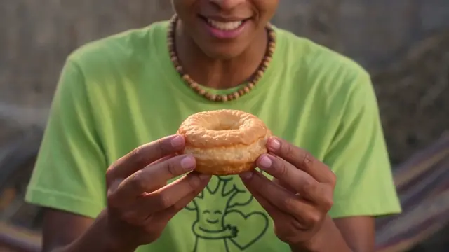Hands holding a doughnut over a green t-shirt